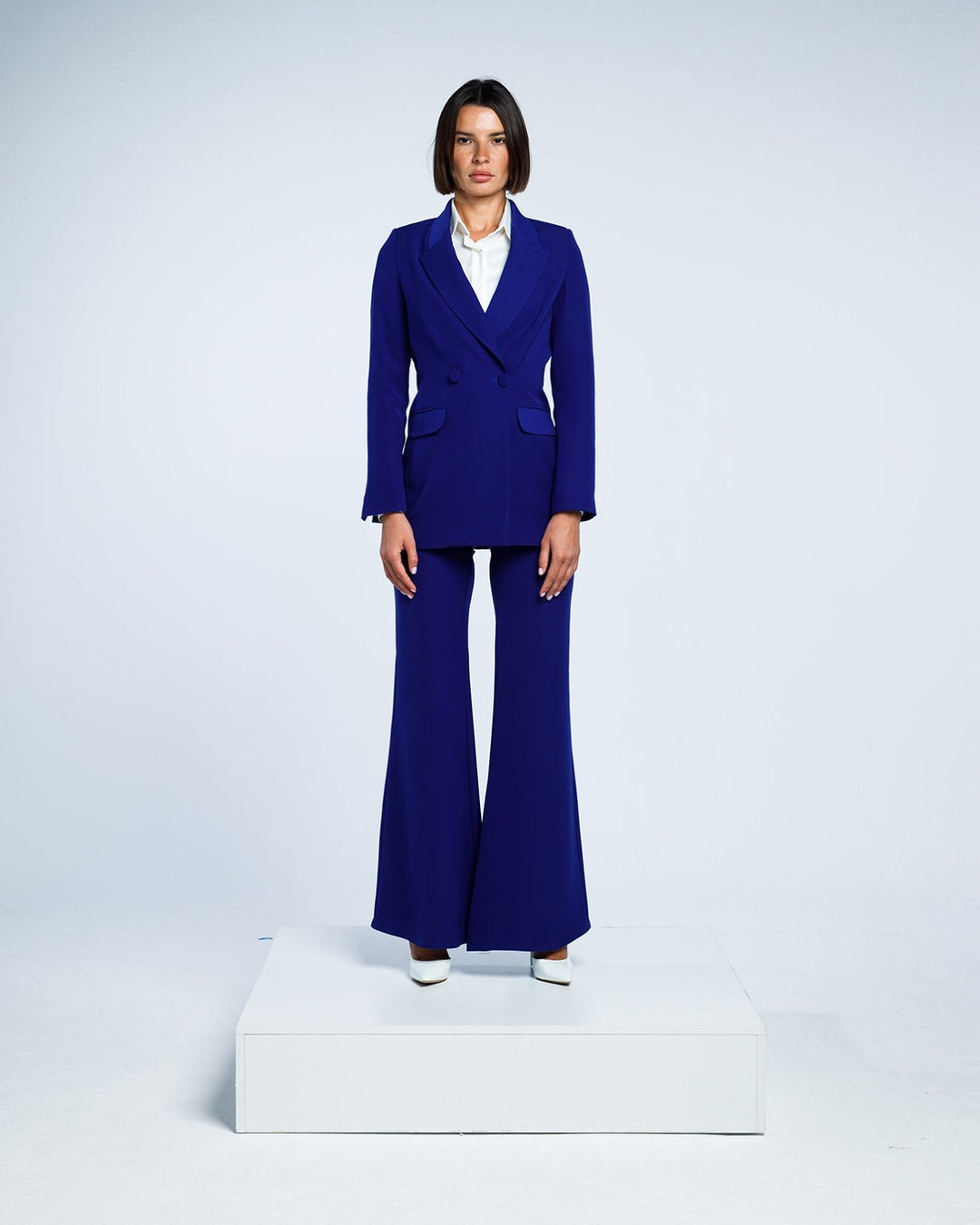 Woman wearing a royal blue tailored pantsuit with flared trousers and a white blouse.