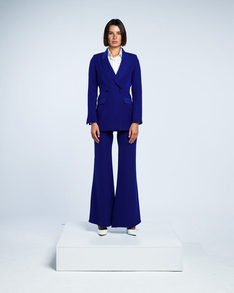 Woman wearing a royal blue tailored pantsuit with flared trousers and a white blouse.