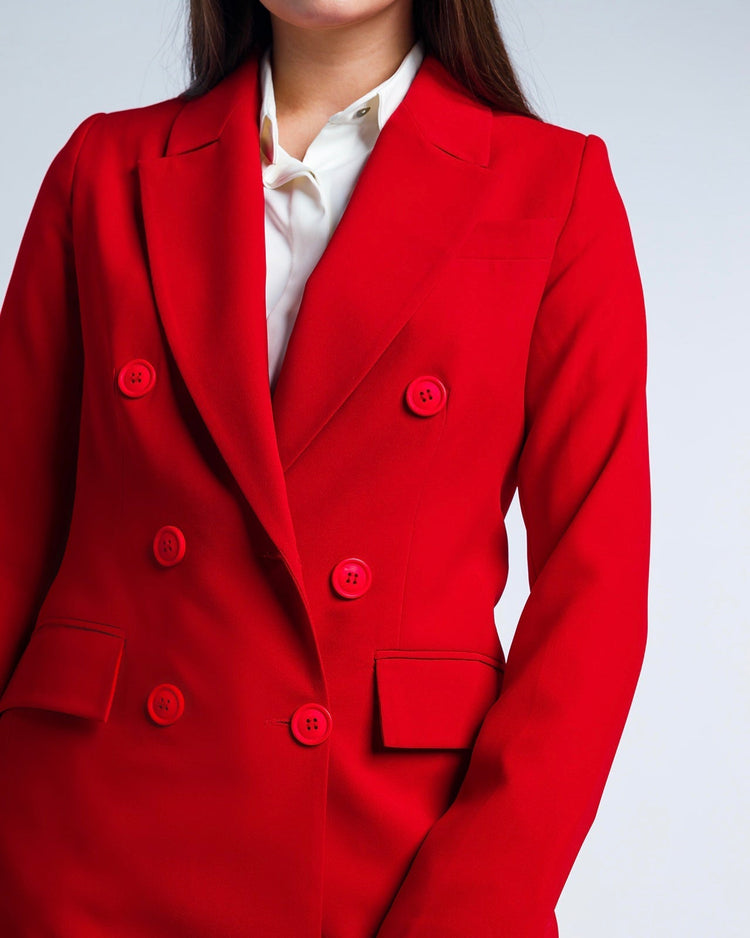 Woman wearing a vibrant red double-breasted blazer over a white blouse