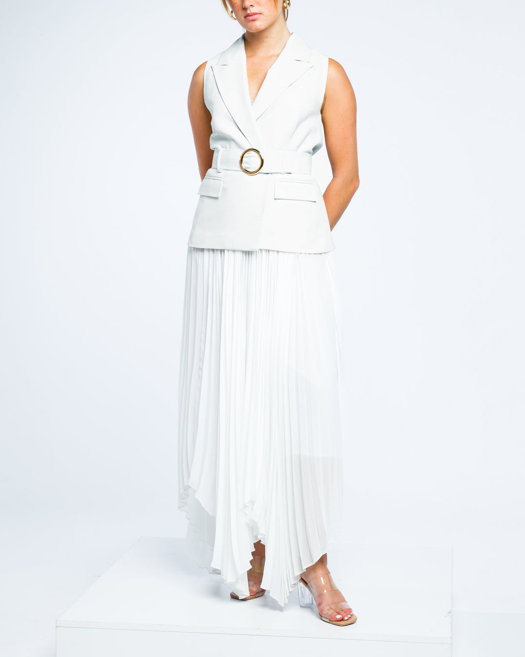 Sleeveless white belted blazer dress with pleated chiffon skirt and clear heels