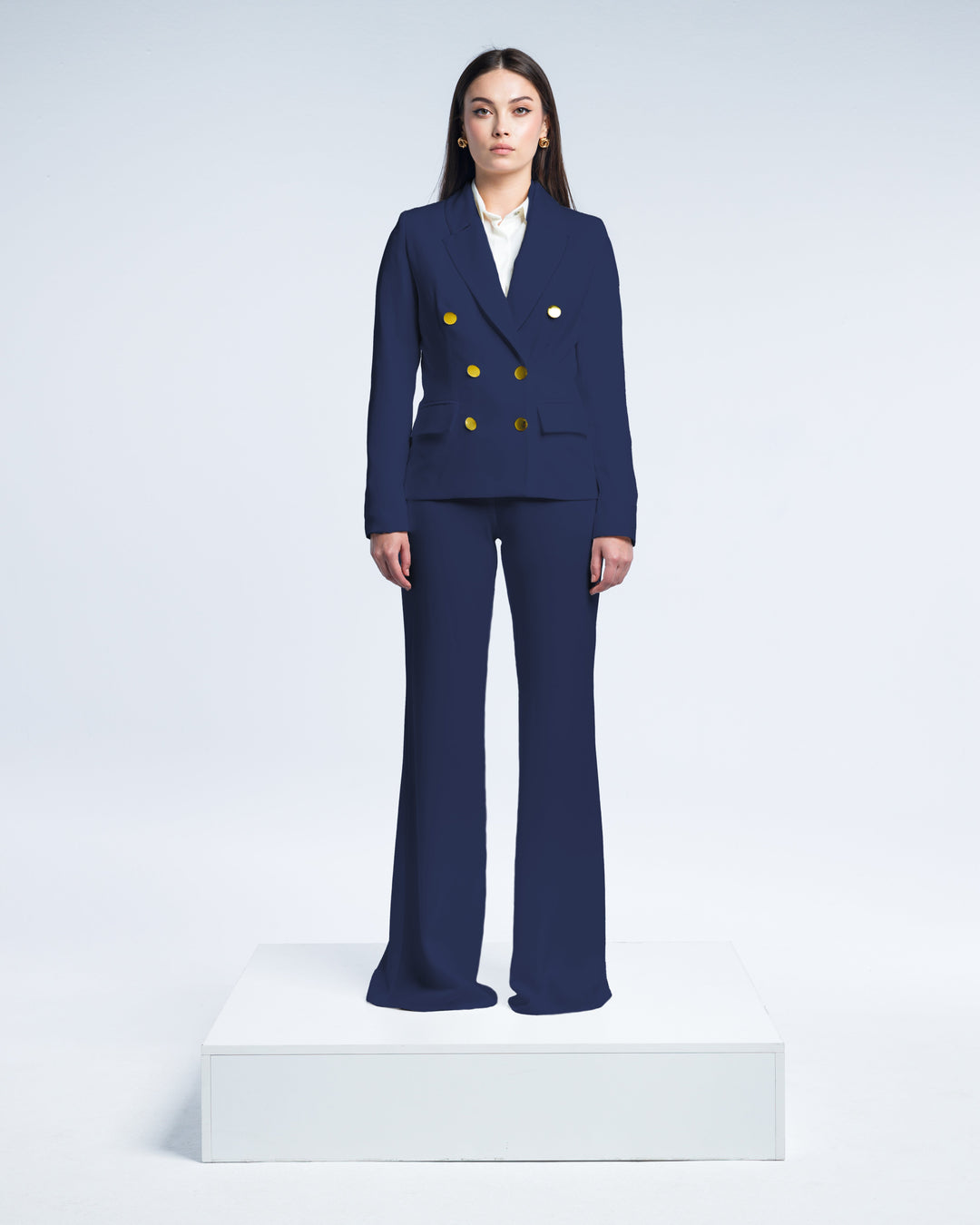 Woman in a tailored navy blue double-breasted pantsuit with gold buttons, white blouse