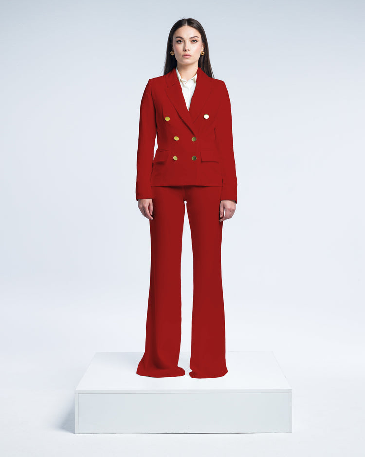 Woman in red double-breasted pantsuit with gold buttons and white blouse, studio background