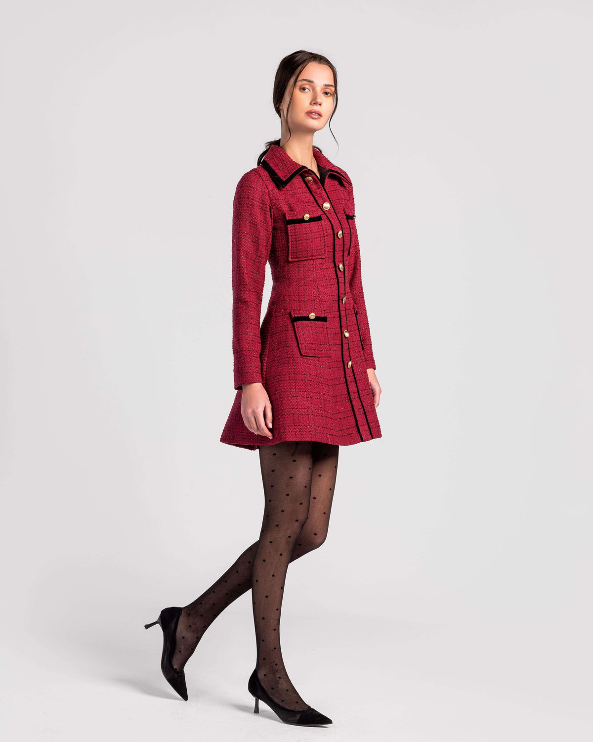 Woman in red tweed mini dress with gold buttons, black polka dot tights, and black heels