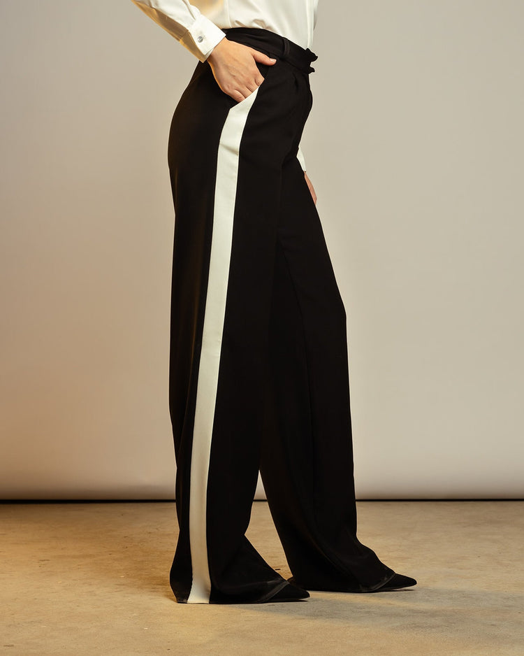 Woman wearing black wide-leg pants with white side stripes and a white blouse