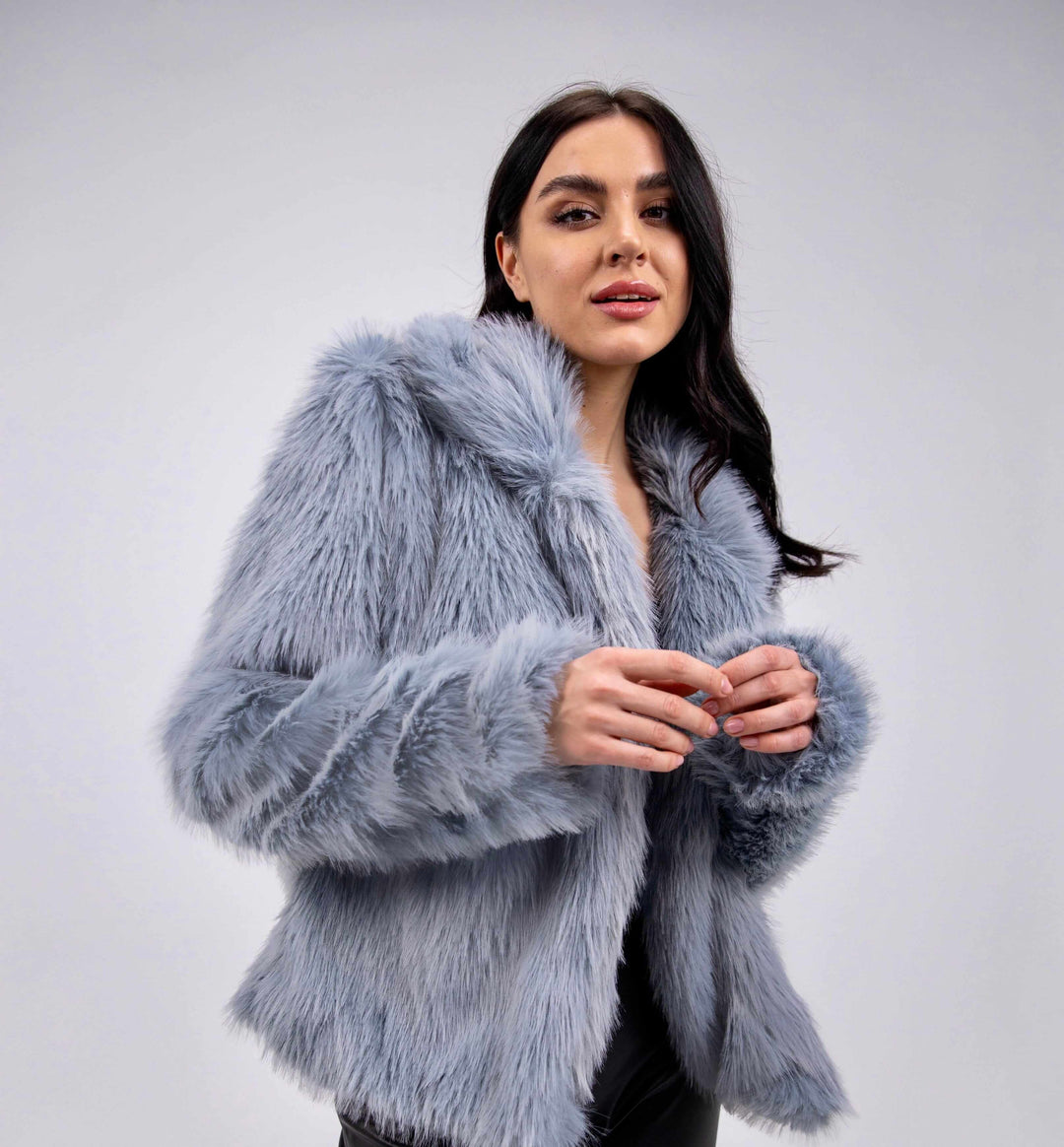 Woman wearing a baby blue faux fur jacket with long sleeves against a plain background
