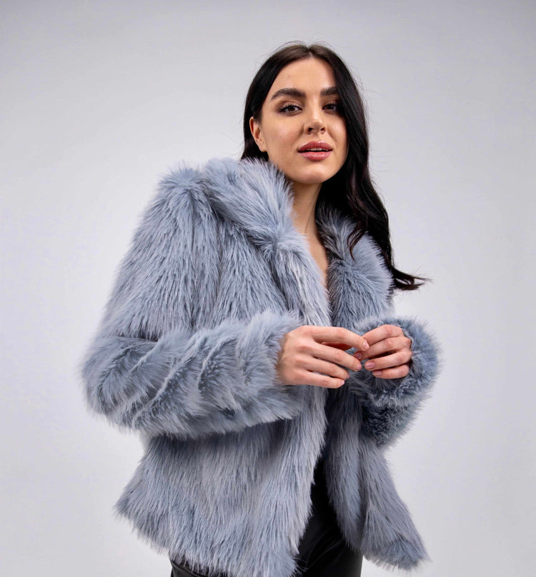 Woman wearing a baby blue faux fur jacket with long sleeves against a plain background