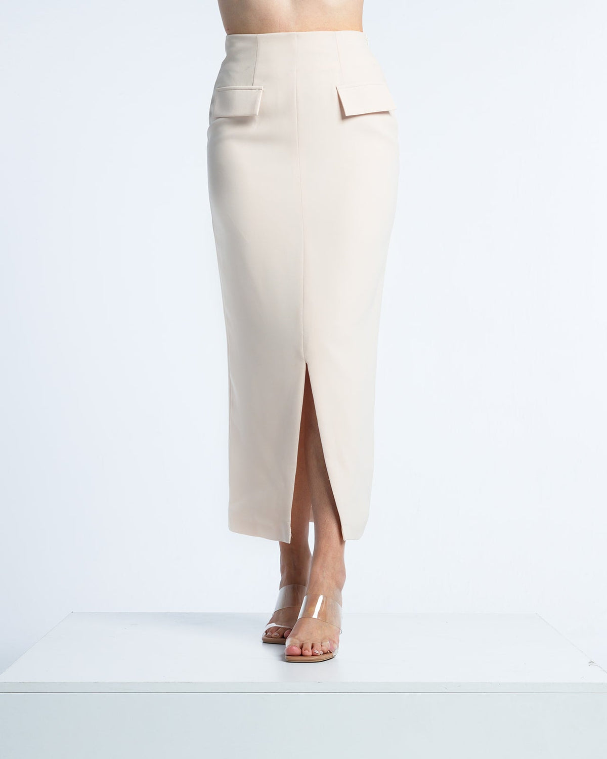 Woman wearing high-waisted beige midi pencil skirt with front slit and flap pockets