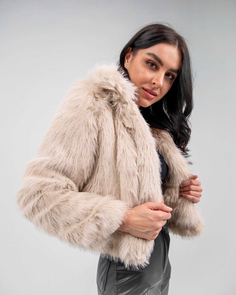 Woman modeling beige faux fur jacket with long sleeves and plush texture