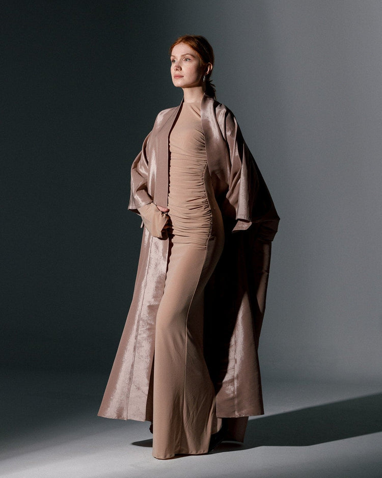 Woman wearing a beige oversized organza kimono over a fitted nude dress in studio lighting