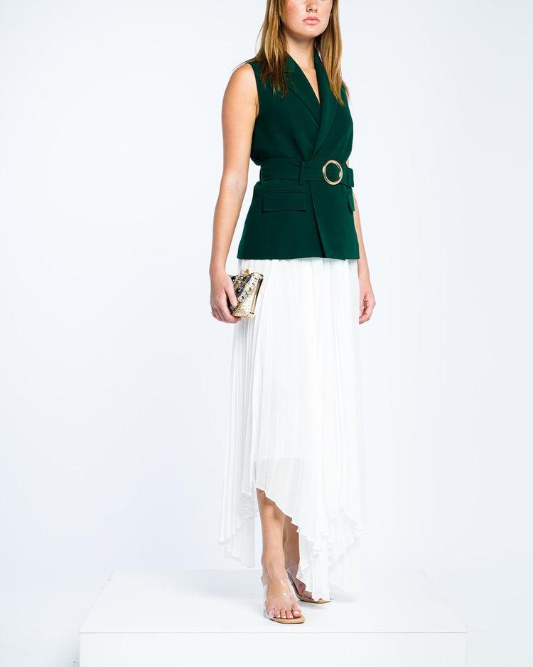 Woman in sleeveless dark green belted blazer and white asymmetrical pleated skirt
