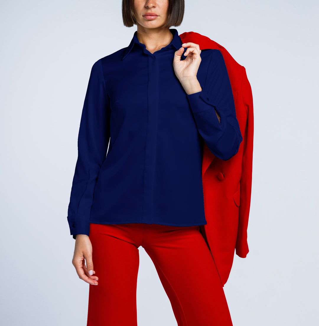 Woman in navy blue shirt and red pants holding matching red blazer, modern fashion style