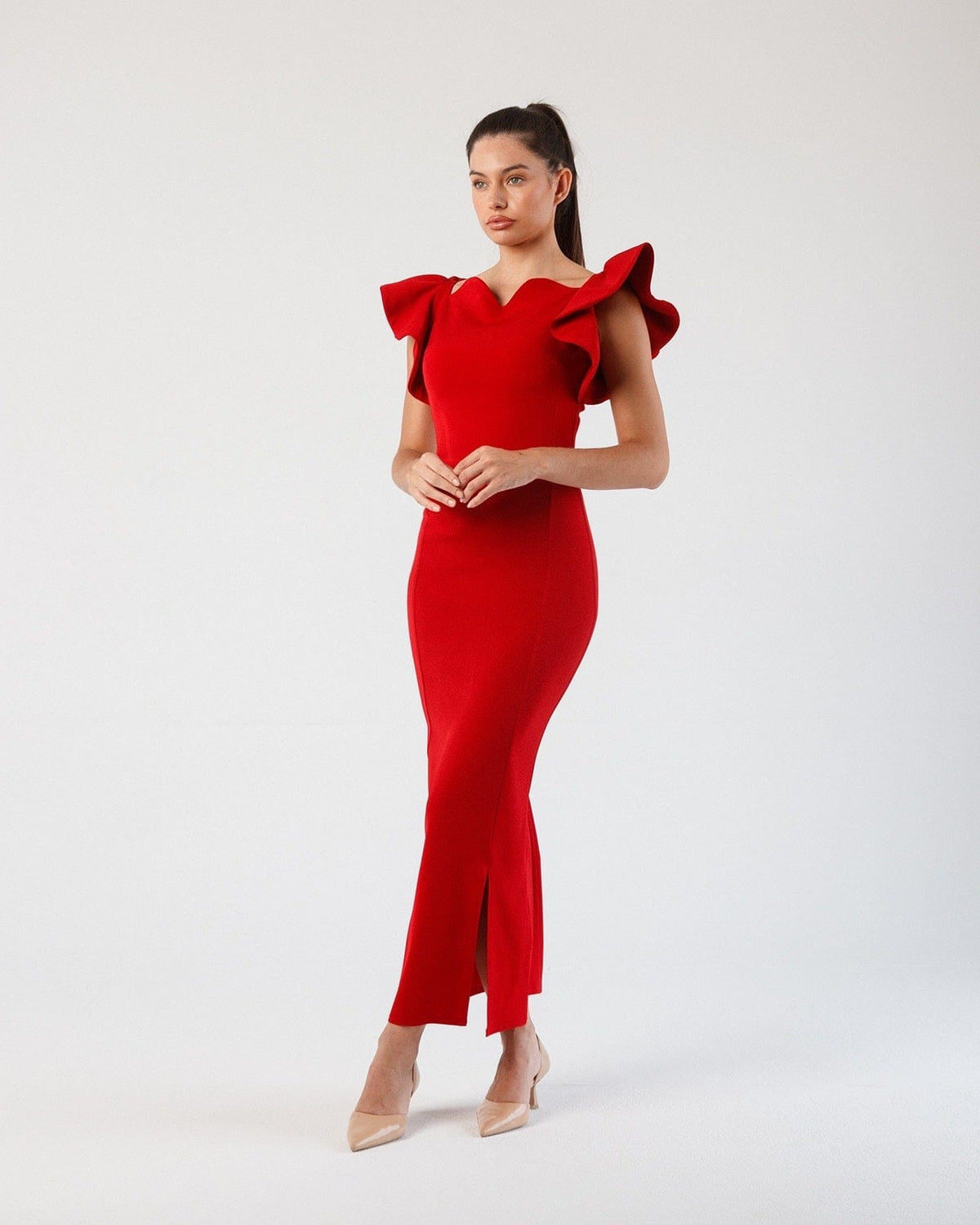 Woman wearing elegant red ruffle sleeve evening dress with front slit, standing indoors