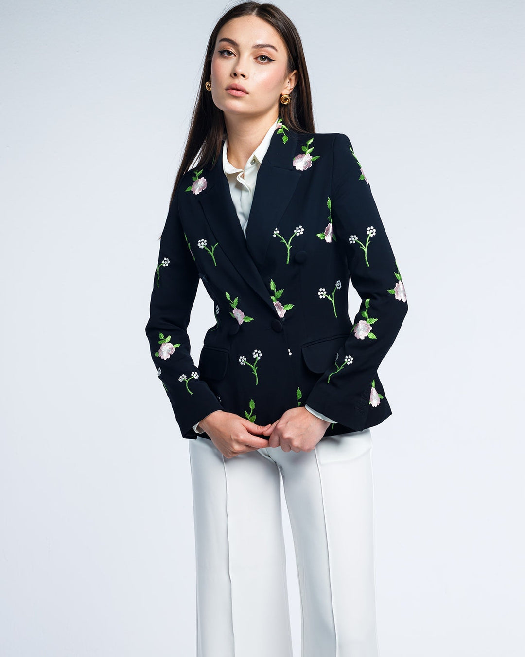 Woman wearing a floral embroidered black blazer and white dress pants, elegant style