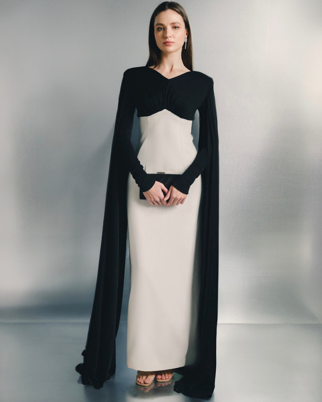 Woman wearing elegant black and white long evening dress with cape sleeves