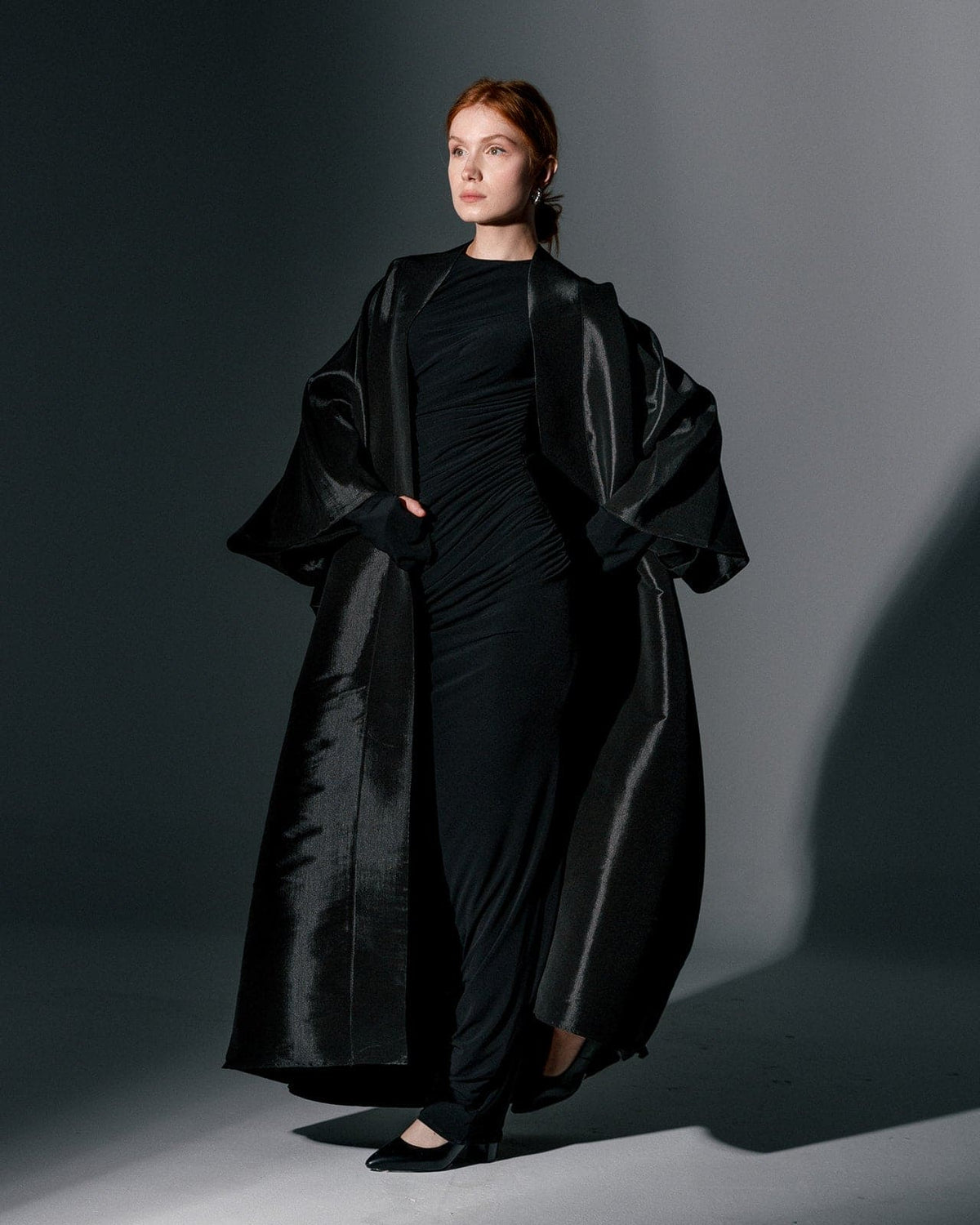 Woman wearing a black oversized organza kimono and black dress in a studio setting