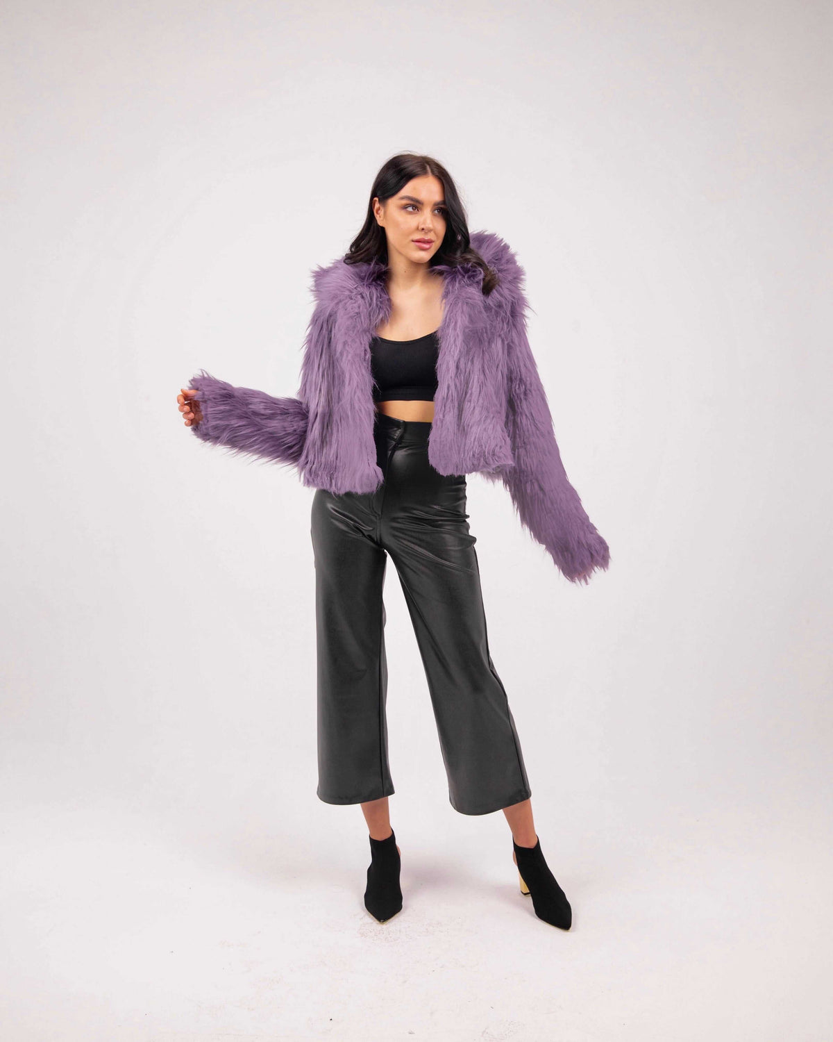 Woman wearing purple faux fur jacket, black crop top, and black wide-leg pants