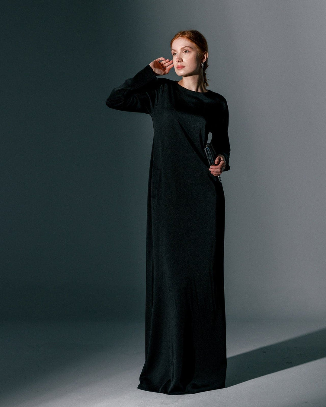 Woman wearing long black formal gown dress in minimal studio setting