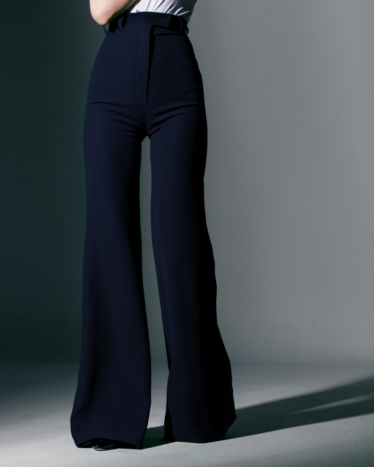 High-waisted black wide-leg pants styled with a white top on a fashion model