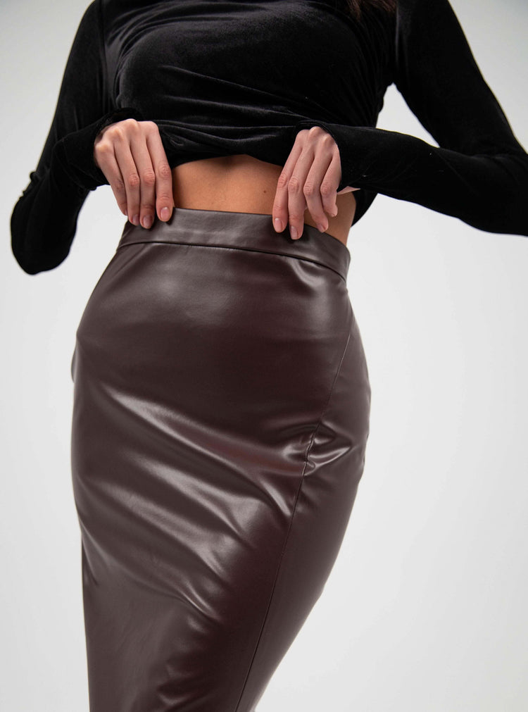 Woman wearing a high-waisted brown faux leather pencil skirt and black velvet top