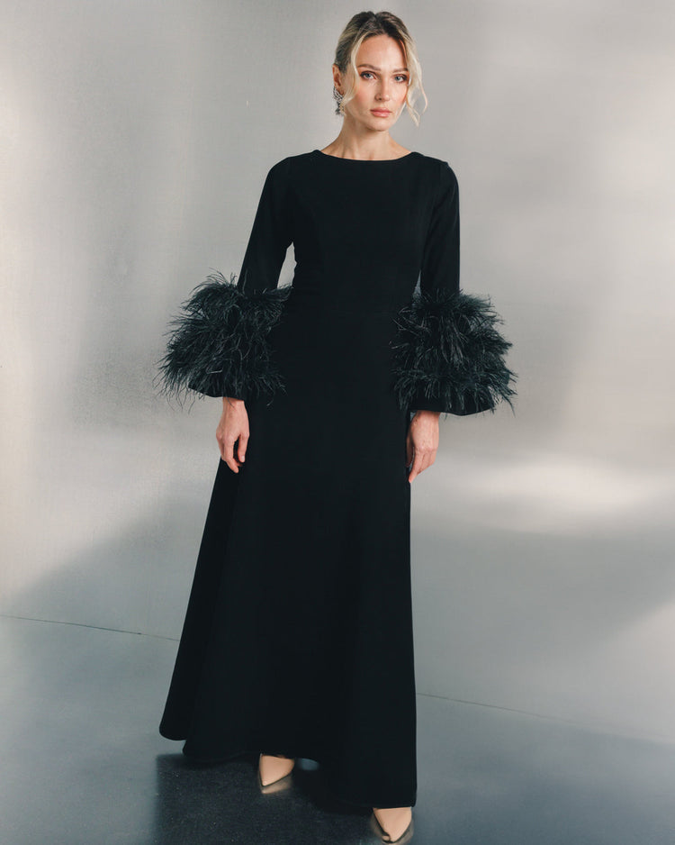 Woman in a long black evening dress with feathered sleeves and nude heels