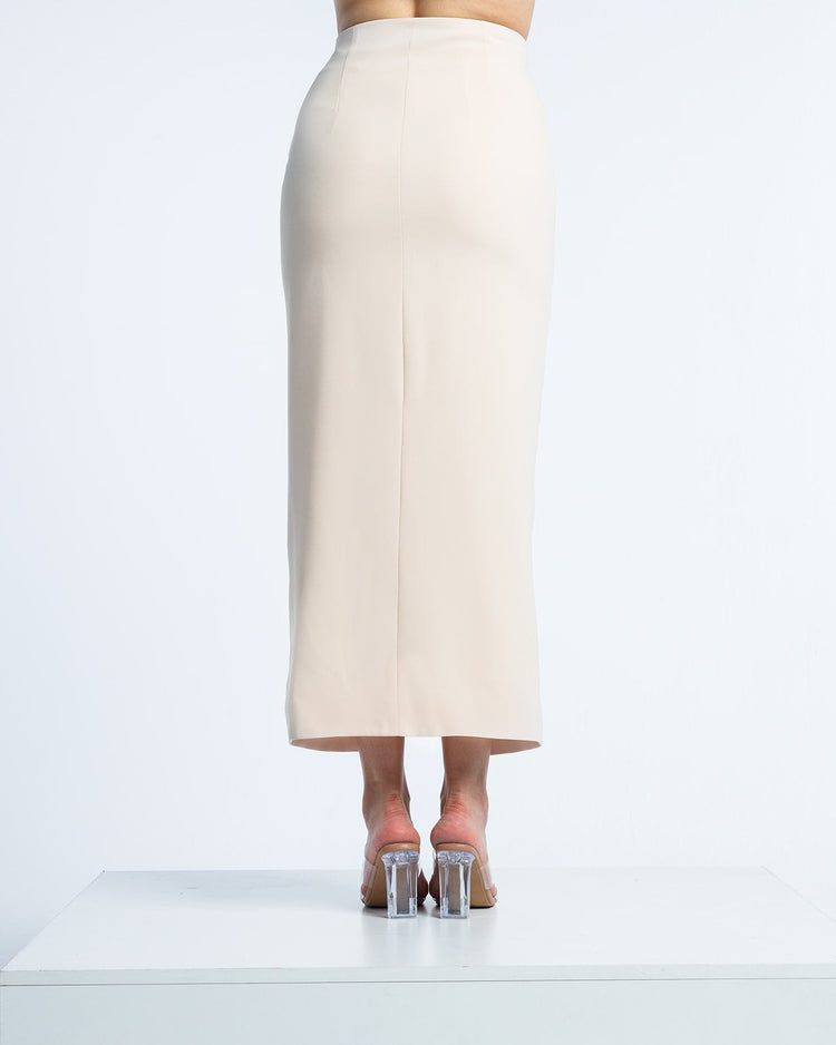 Back view of woman in high-waisted beige midi pencil skirt and clear block heels
