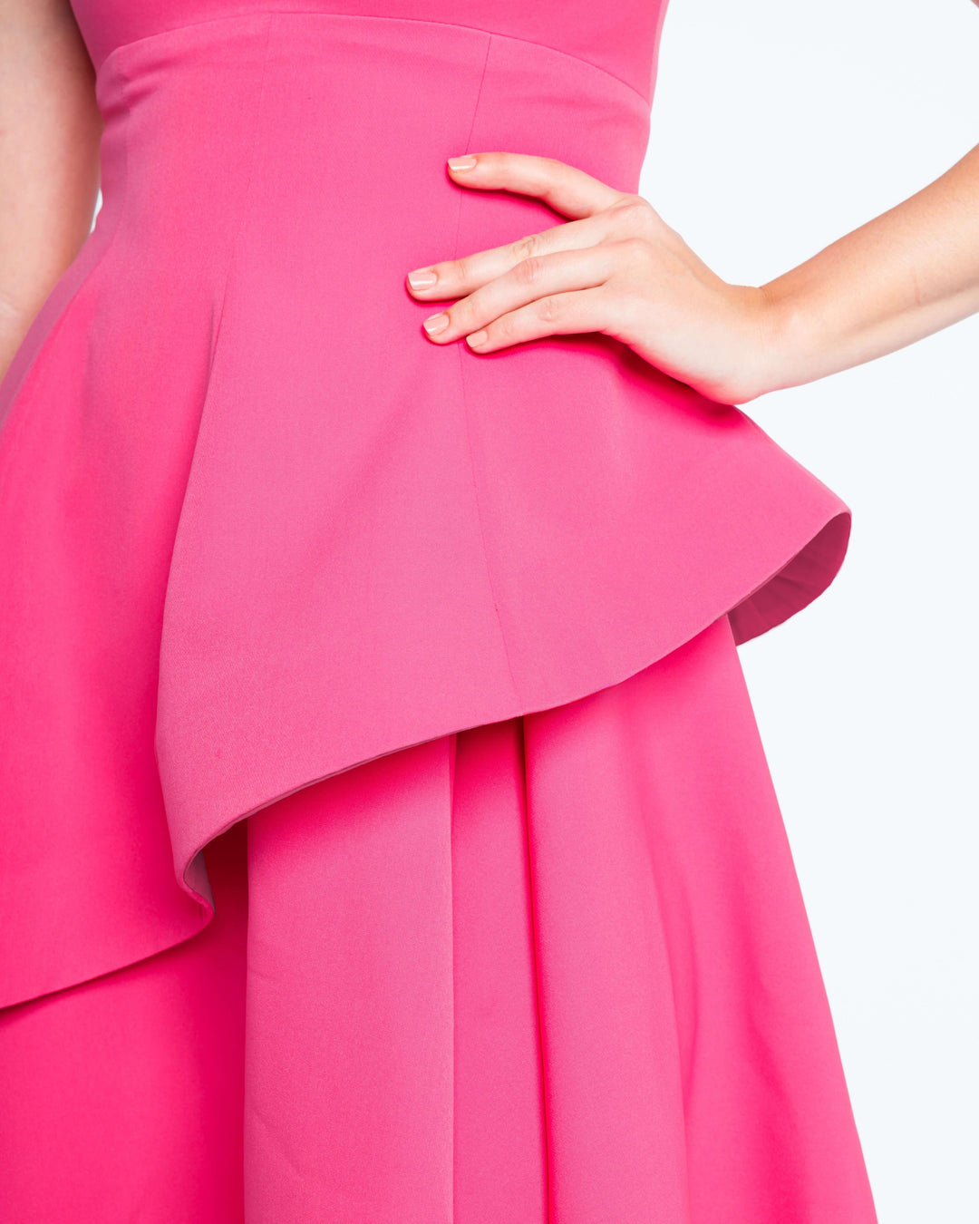 Woman wearing vibrant fuchsia pink dress with structured peplum and hand on hip