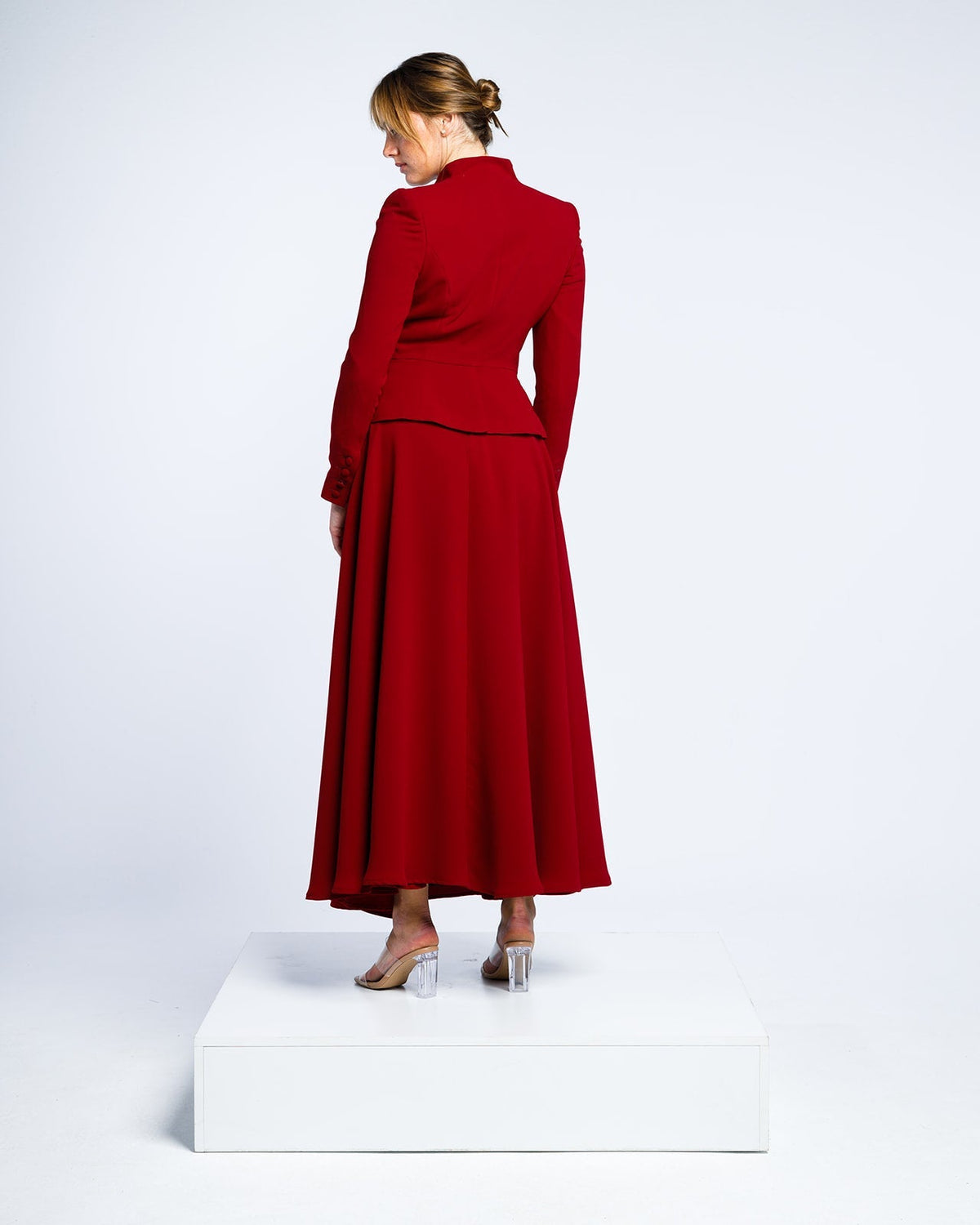 Woman modeling an elegant long red suit dress with flared skirt and fitted blazer