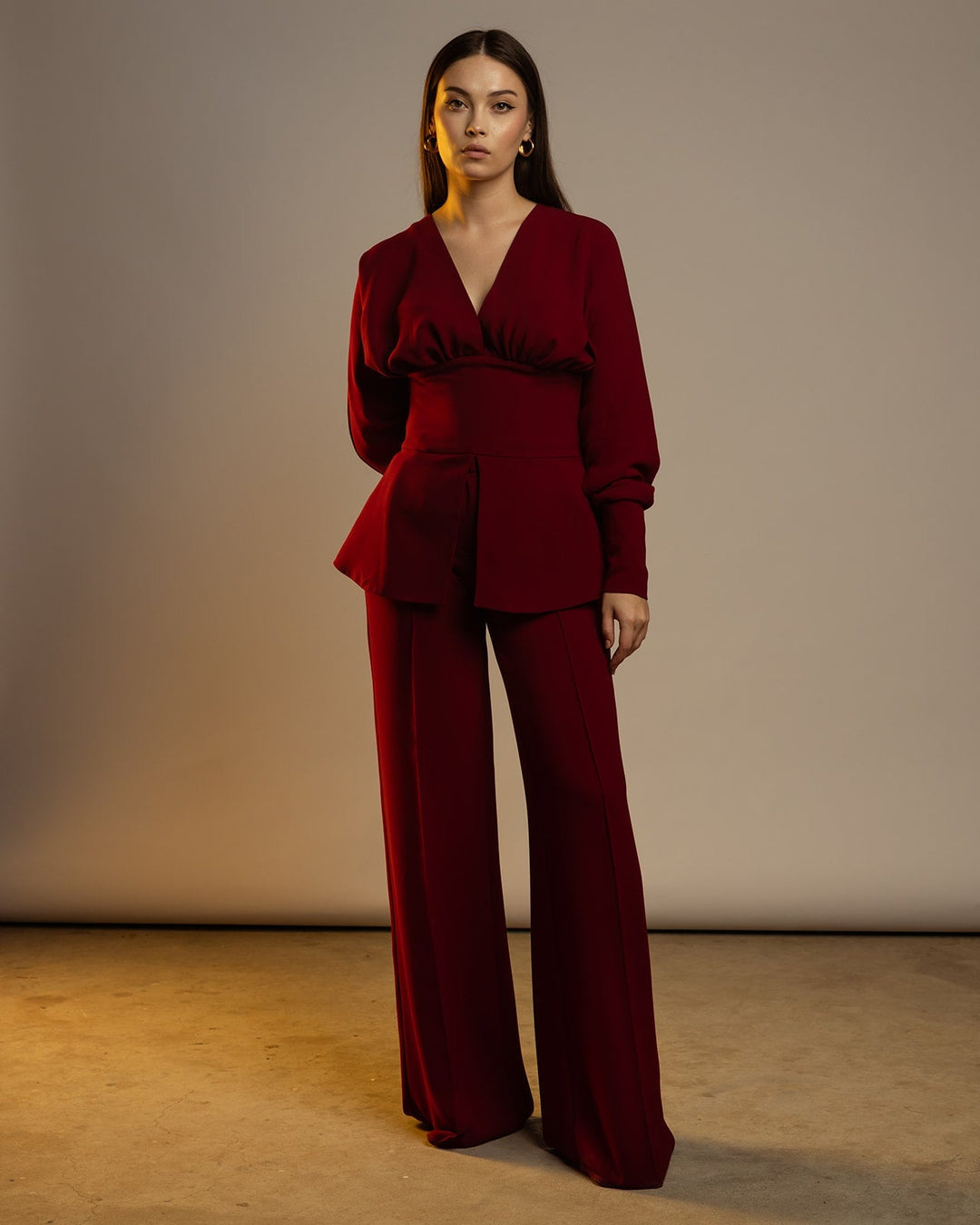 Woman wearing elegant maroon pantsuit with long sleeves and wide-leg trousers, fashion style
