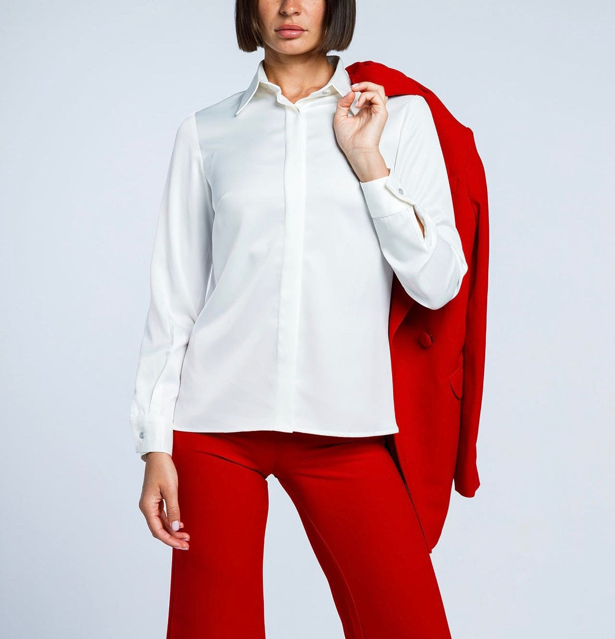 Woman in white dress shirt and red pants with red blazer over shoulder, fashion outfit
