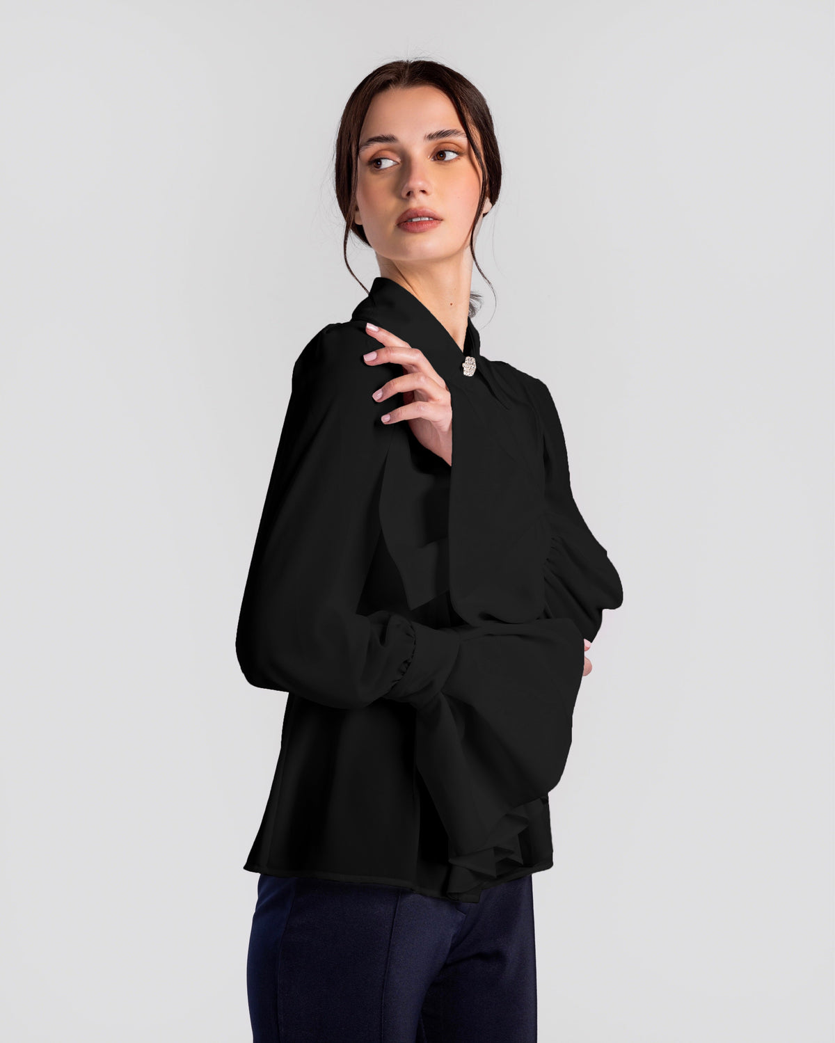 Woman wearing elegant black long sleeve blouse with large bow collar and wide cuff sleeves.