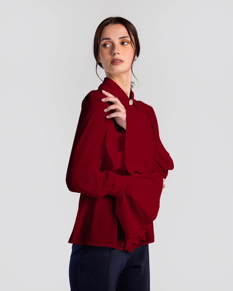 Woman wearing elegant maroon long-sleeve blouse with statement collar and flared cuffs