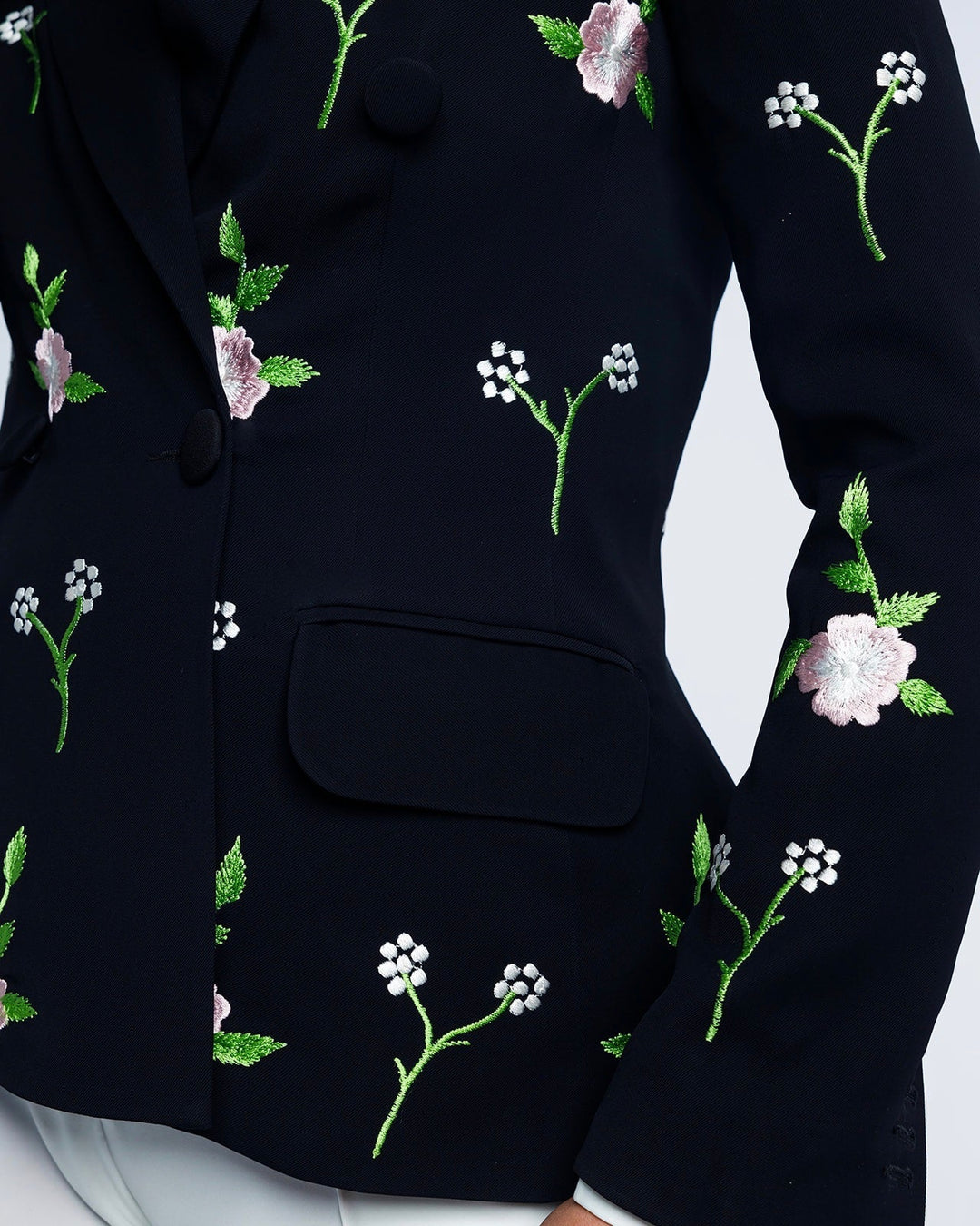 Close-up of black blazer with pink and white floral embroidery, elegant fashion style