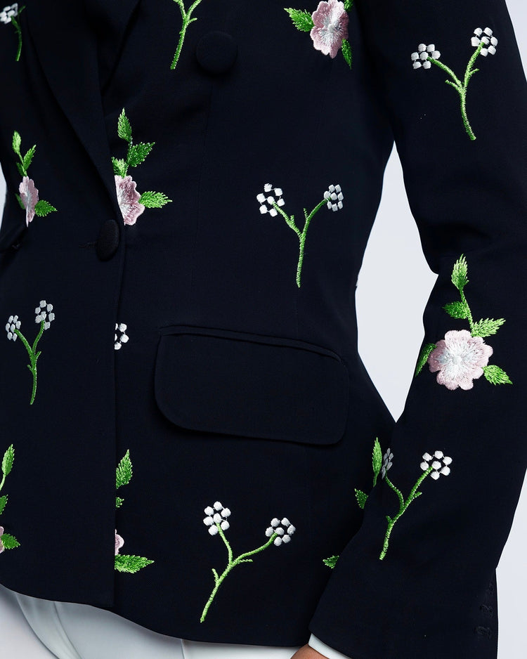 Close-up of black blazer with pink and white floral embroidery, elegant fashion style