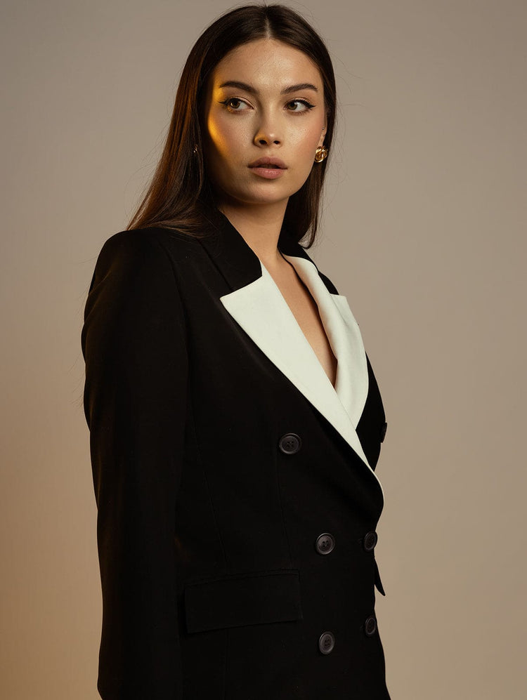 Woman in black double-breasted blazer with white lapel, elegant formal fashion