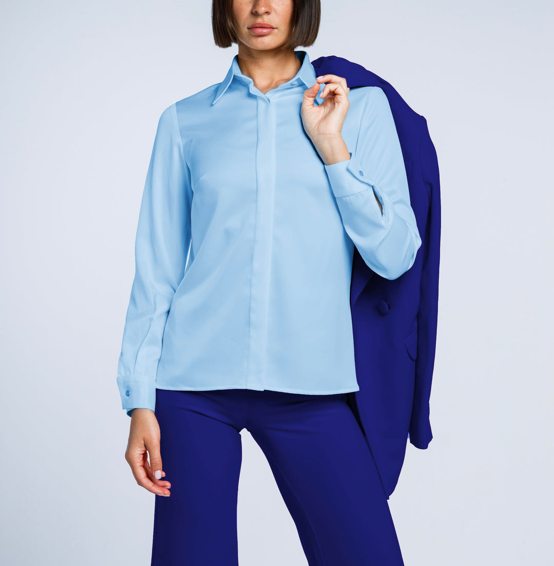 Woman in light blue long-sleeve shirt and blue tailored pants with blazer