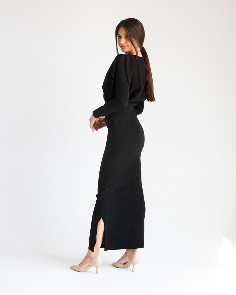 Woman in long black elegant dress with side slit and nude heels on white background