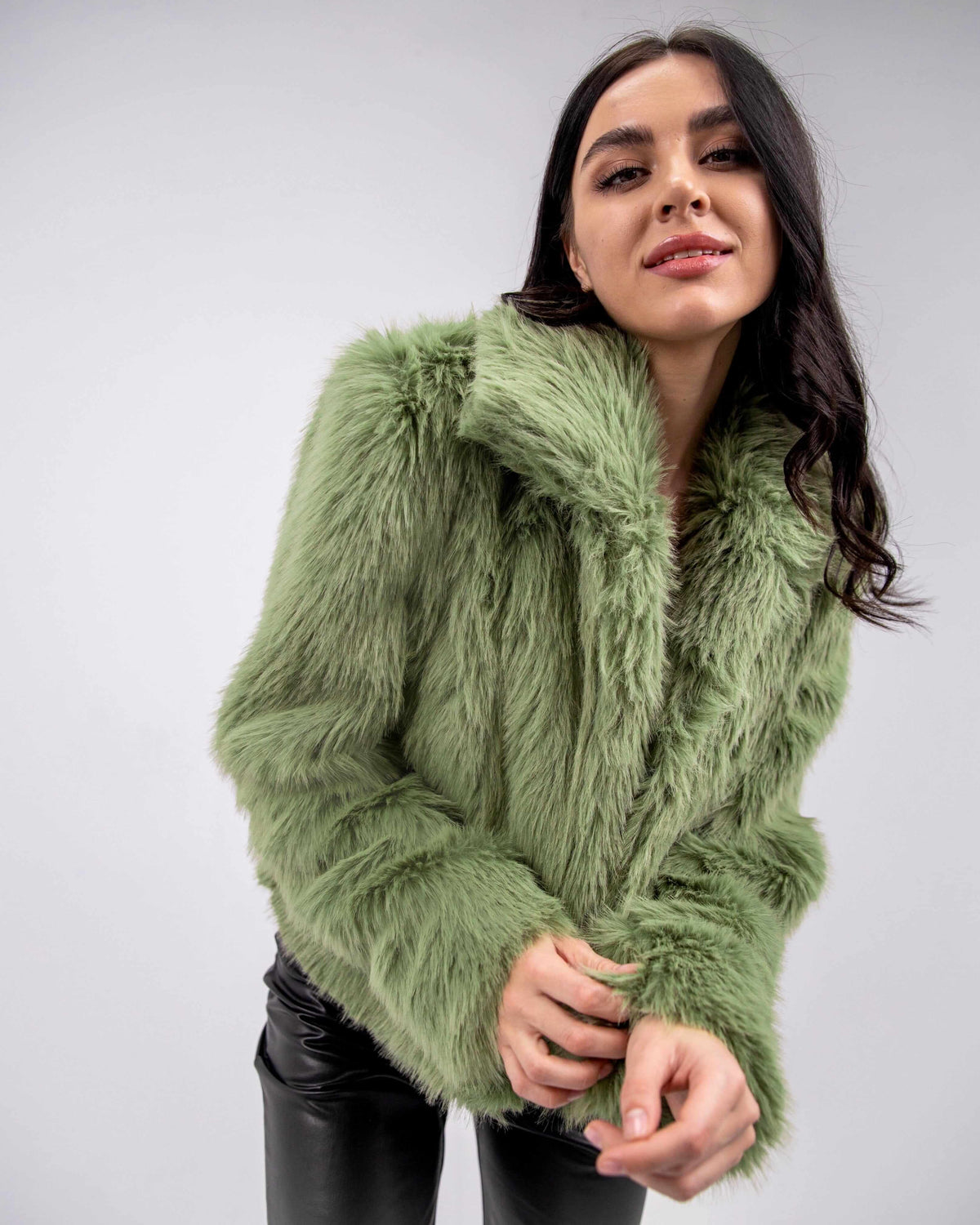 Woman wearing an olive green faux fur jacket and black leather pants, stylish winter fashion