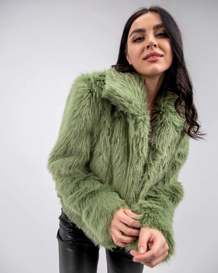 Woman wearing an olive green faux fur jacket and black leather pants, stylish winter fashion