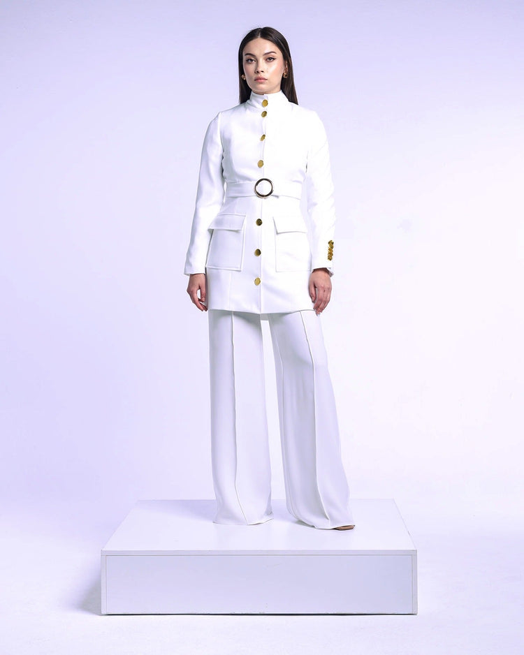 Woman wearing an elegant white tailored suit with gold buttons and wide-leg pants on a platform