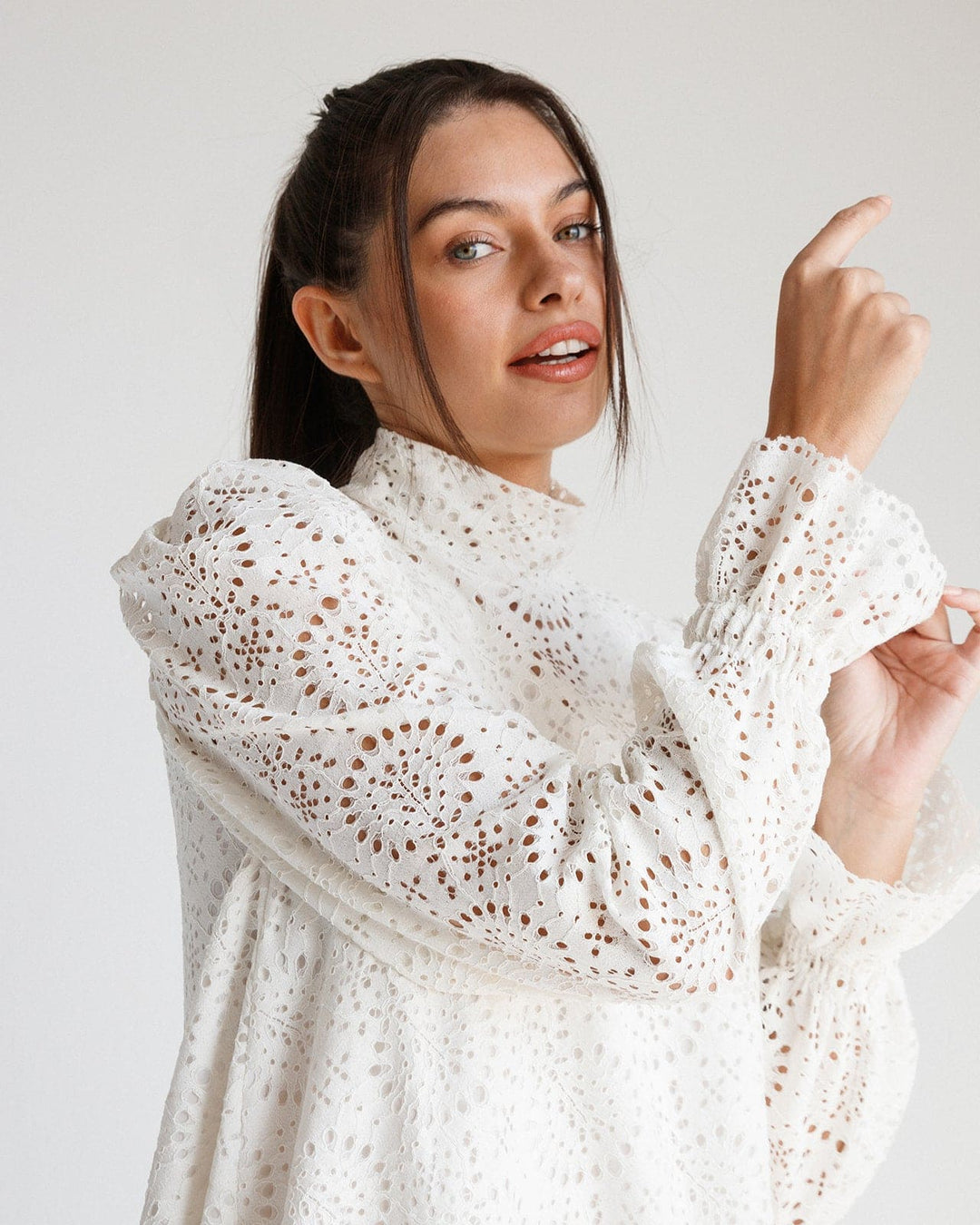 Woman wearing a white lace long sleeve dress with high neck and puffed sleeves