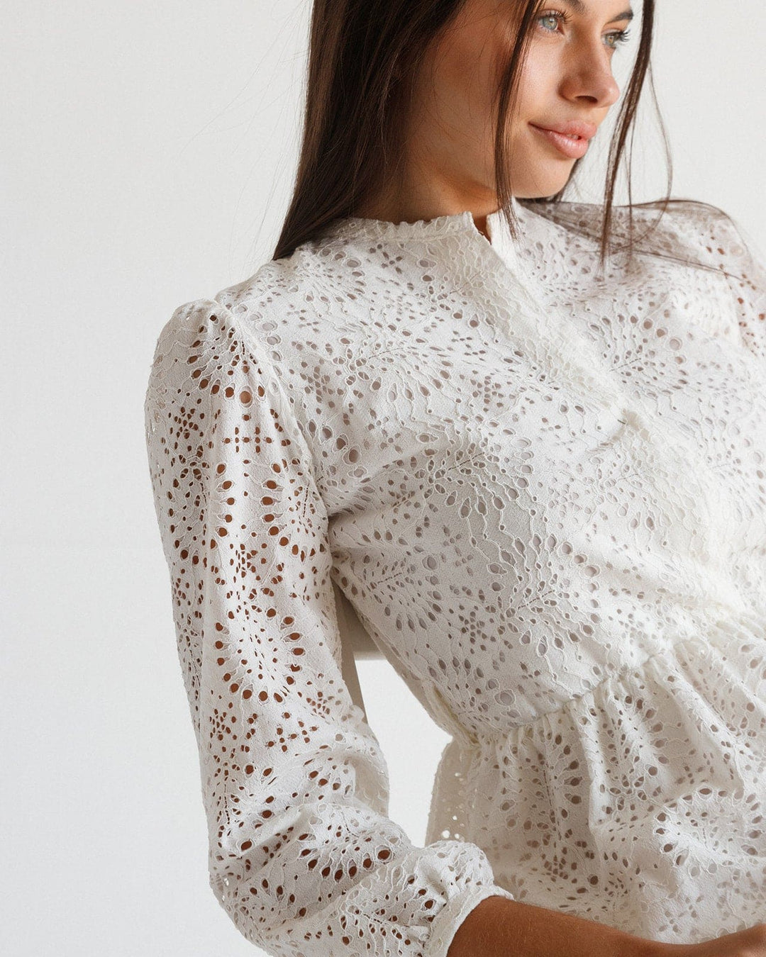 Woman wearing an elegant white eyelet lace dress with long sleeves and scalloped neckline