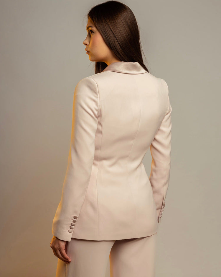 Woman wearing a cream rose tailored blazer suit, viewed from the back, studio lighting