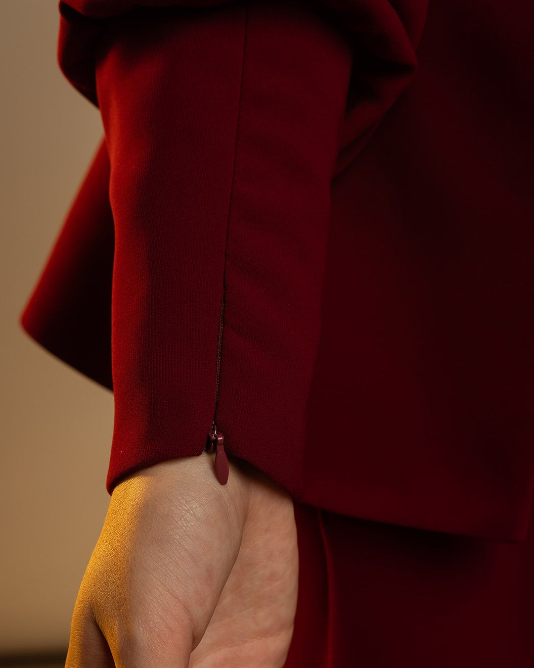 Close-up of a woman's hand in an elegant maroon dress sleeve with cuff zipper detail