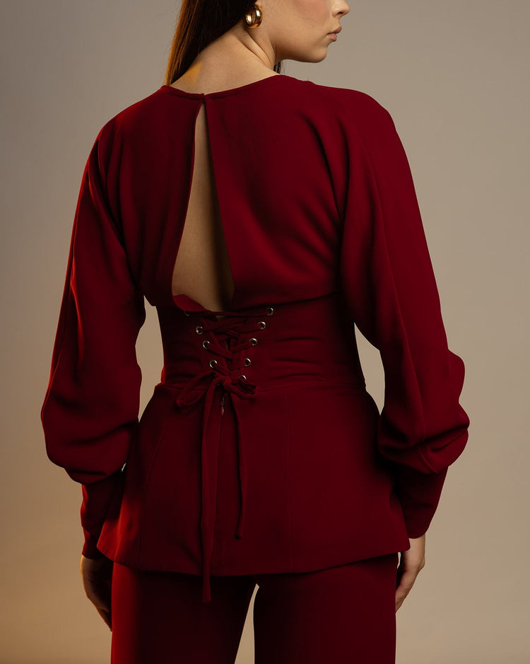 Woman wearing a backless maroon blouse with lace-up detail and long sleeves