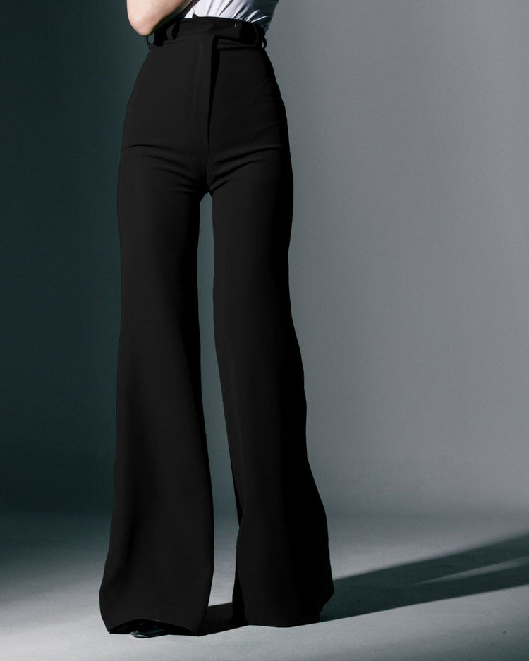Woman wearing high-waisted black wide-leg trousers and a white tucked-in top