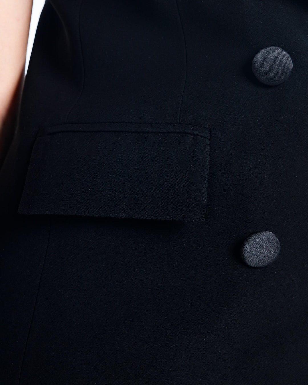 Close-up of tailored black suit with flap pocket and fabric-covered buttons