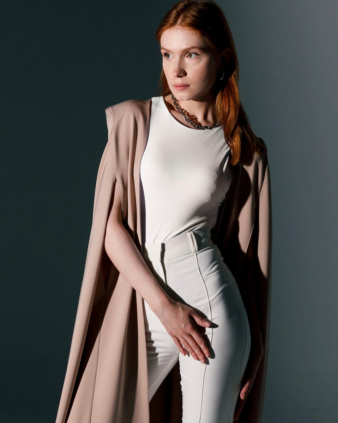 Woman in beige crepe cape gown with white top and high-waisted pants, elegant fashion style