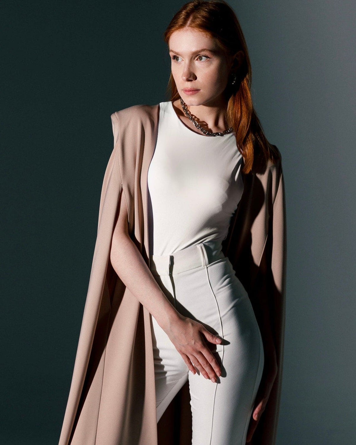 Woman in beige crepe cape gown with white top and high-waisted pants, elegant fashion style