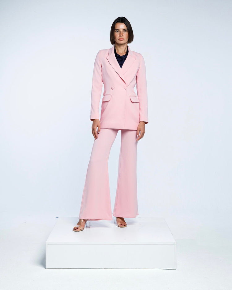 Woman modeling a tailored light pink pantsuit with flared trousers in a studio setting