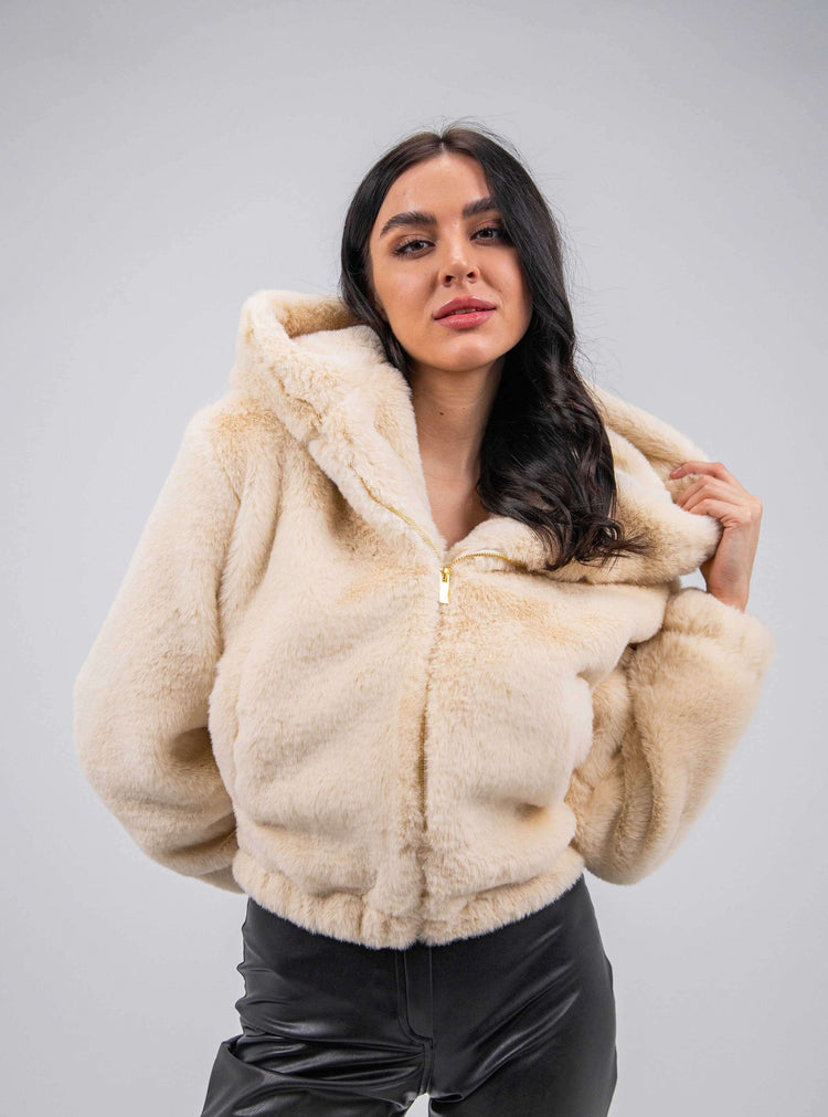 Woman wearing a beige faux fur hooded jacket with black leather pants, stylish fashion look